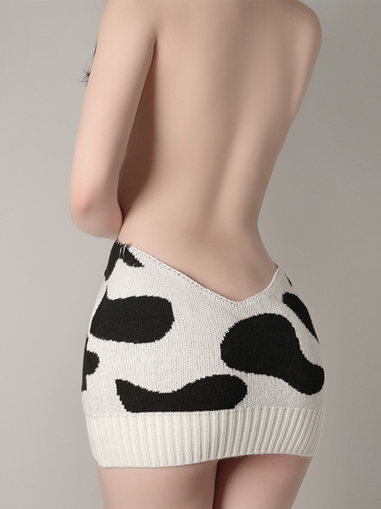 Back view of a halter neck cow print knit dress featuring an open back design and bold black and white cow pattern