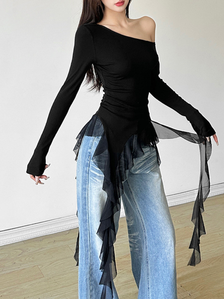 Person wearing a black off-shoulder top and light blue jeans with ruffled details.