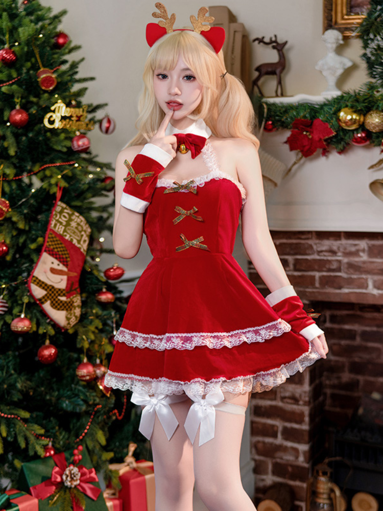 Woman in a Velvet Lace Bow Red Christmas Lingerie Dress Halter Mini Babydoll with reindeer ears standing in front of a decorated Christmas tree.