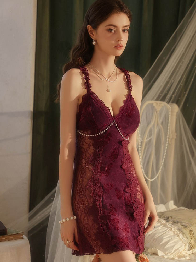 Woman wearing a burgundy lace dress with pearl details in an indoor setting.